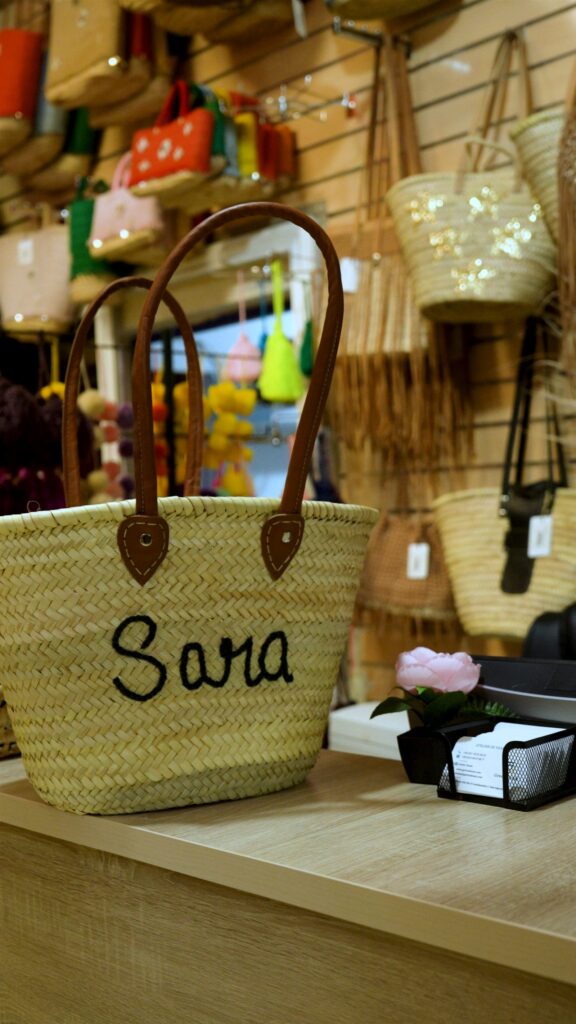 Straw basket with leather handles personalised with the name Sara in black stitching